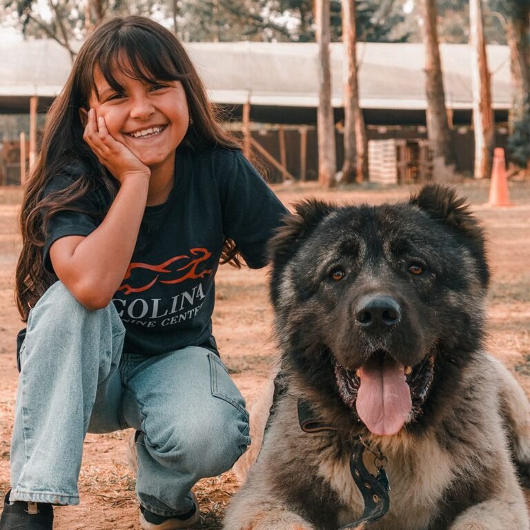 Niña sonriendo junto a un perro en Colina Canine Center